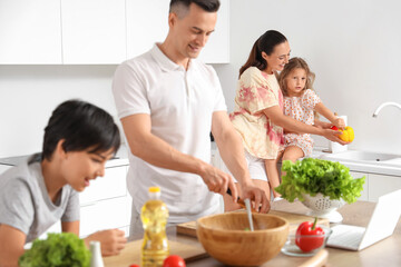 Happy mother with her little daughter washing bell peppers in kitchen