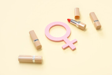 Female gender symbol and lipsticks on beige background