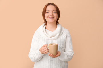 Young woman with cup of coffee on beige background