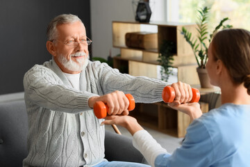 Senior man with dumbbells and nurse training at home