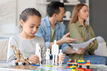 Sad little girl with family figure and her parents getting divorce at home