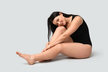 Obraz premium Body positive young woman sitting on light background