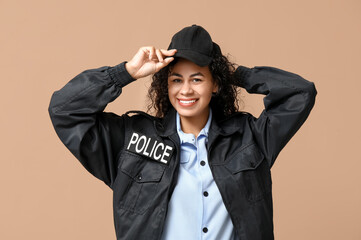 Beautiful young happy African-American policewoman on brown background