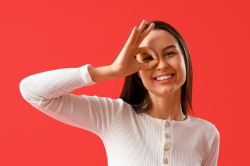 Young woman showing OK on red background, closeup