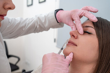 Beautician injecting Botox for nose beauty treatment: cosmetic procedure for skin rejuvenation and...