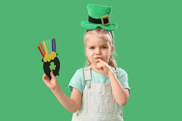 Cute little girl with leprechaun's hat holding paper pot with coins on green background. St....