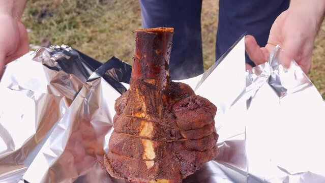 Experienced man wraps succulent grilled meat in foil, keeping it juicy. Each fold of foil retains the smoky flavor for a delicious grilling experience. The concept of cooking juicy beef on the grill.