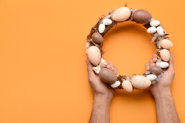 Male hands holding  Easter wreath on orange background
