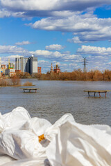The flooding of the city embankment of the Tobol River with white sandbags piled in front for protection in Kurgan, Russia. Focus on the background. 	