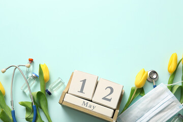 Stethoscope with mask, ampules and yellow tulips for International Nurses Day on turquoise background