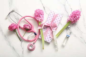 Stethoscope with ampules, gift box and flowers for International Nurses Day on white grunge background