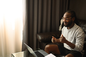 Happy millennial African man in glasses having virtual meeting communicating by video call
