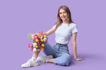 Happy young woman with bouquet of beautiful tulips sitting against lilac background