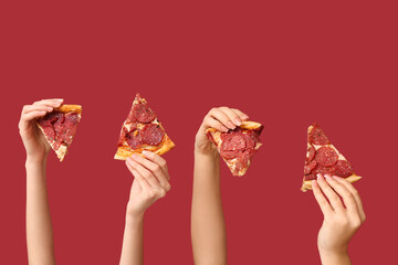 Many hands holding pizza slices on red background
