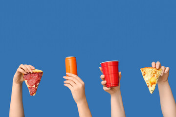 Many hands holding tasty pizza slices, one-use cup and can of soda on blue background