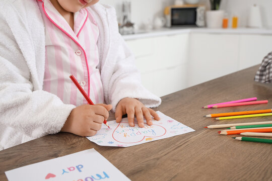 Cute little girl drawing greeting card to Mothers Day at table in kitchen