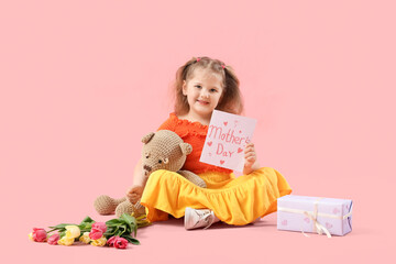 Little girl with greeting card, tulips and plush toy on pink background. Mothers Day concept
