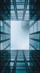 Modern architecture with glass facade reflecting sky. Upward perspective of skyscraper with foggy background