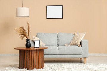Stylish living room with sofa and blank picture frame on beige wall