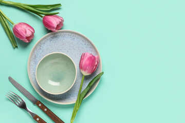 Table setting with tulips on turquoise background. Mother's day concept