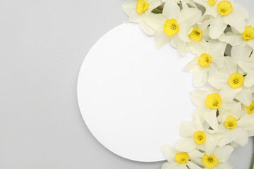 Composition with daffodil flowers and blank card on grey background. Top view