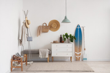 Stylish interior of modern hall with bench, chest of drawers and surfboard