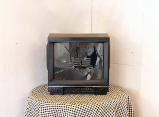 A broken television on a round table in the corner of the room