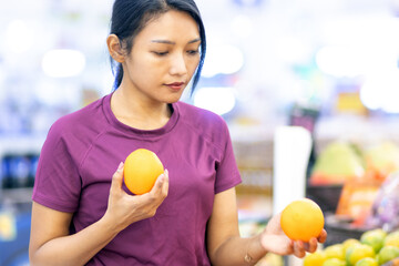 A young woman in a store chooses fresh oranges