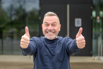 Enthusiastic motivated attractive middle aged man giving a double thumbs up gesture