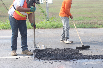 two men are working on a road with a shovel