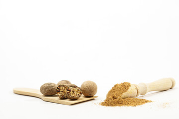 whole nutmeg, halved and ground, on a wooden spoon isolated on a white background and copy space
