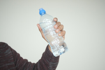 A person is grasping a plastic bottle with their fingers and thumb