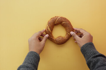 top view of hand holding Turkish Bagel Simit on table 