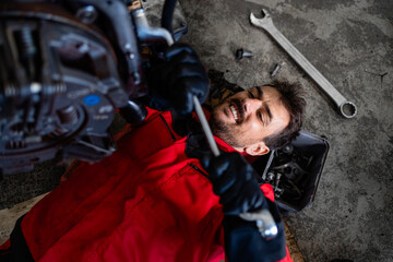 Experienced mechanic working under vehicle repairing the engine in workshop.