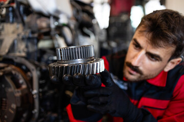 Experienced mechanic or serviceman holding gears parts inside workshop.