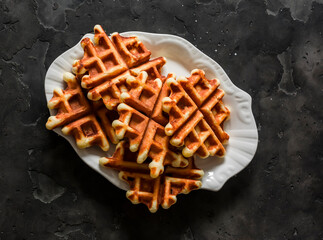 Orange peel and dried apricots waffles on a dark background, top view - 789882903