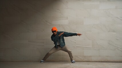Motion shot of hipster perform break dance at gray background. Street dancer practice hip hop...