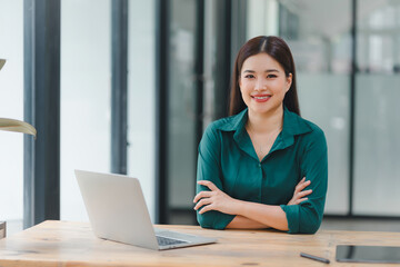 Confident young asian business woman using laptop at modern office.