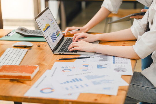 Professional working intensively on a financial analysis with colorful charts and data spreadsheets displayed on a laptop.