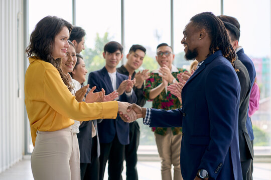 Businesswoman in yellow shirt and African american businessman shake hand together for leadership concept in seminar room.