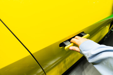 Man's hand opening the door of a modern electric car. The new EV car door handle has a modern...