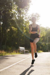 A fit female runner enjoying a morning jog in a serene park, surrounded by lush greenery and soft...