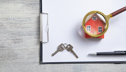 Magnifying glass, house model, pen, keys on the clipboard.