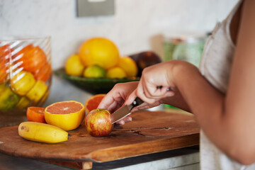 Knife, fruits or hands of woman in kitchen for healthy choice, salad meal or vitamin c in home or...