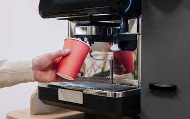 Hand filling red cup at coffee machine