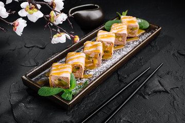 Exquisite sushi roll with kiwi and banana platter with blossoms