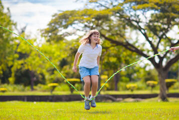 Happy kids play outdoor. Children skipping rope. - 789942365