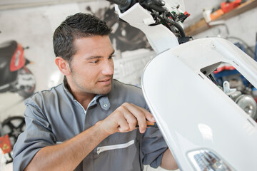 a mechanic is servicing a scooter