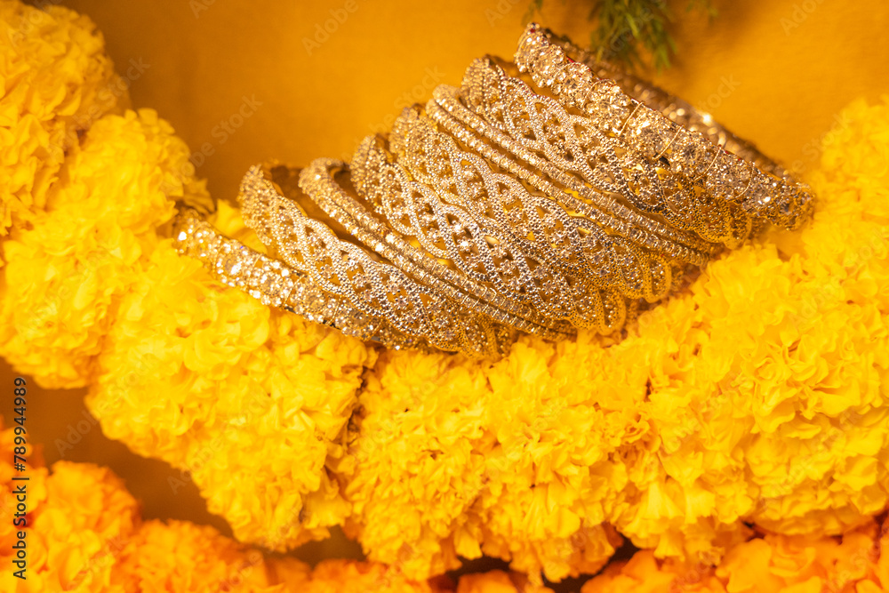 Wall mural stone studded intricate bangles spread on yellow marigold flowers