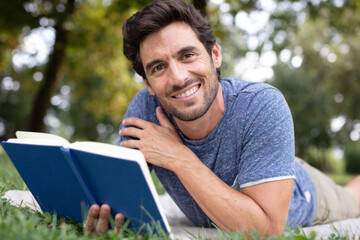 man reading a book on the grass